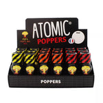 on voit sur un fond blanc un présentoir en carton noir du poppers Atomic. On voit plusieurs flacons jaune orange et rouge, ils ont tous une image d'un champignon atomique sur leur flacon.